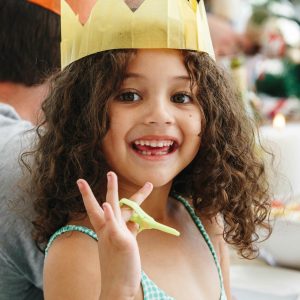 Joyful child wearing a paper crown at a festive gathering